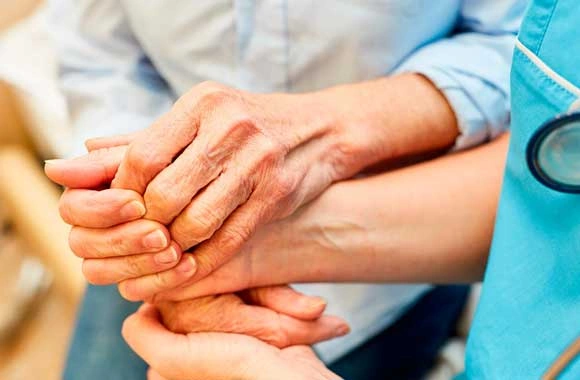 Senior patient holding hands with a caregiver representing nursing home neglect investigations